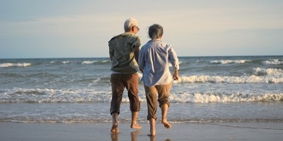 Man and Woman holding hands walking on the beach