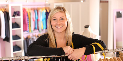 Lady smiling while standing near clothing rack