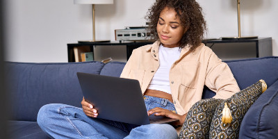 a female sitting on a couch with her laptop