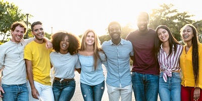 Group of friends, men and women, standing together with arms around each other