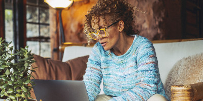 lady wearing glasses sitting on comfy furniture working on laptop