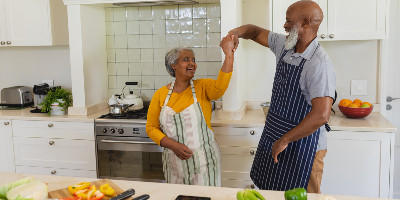 Senior couple dancing in kitchen while cooking