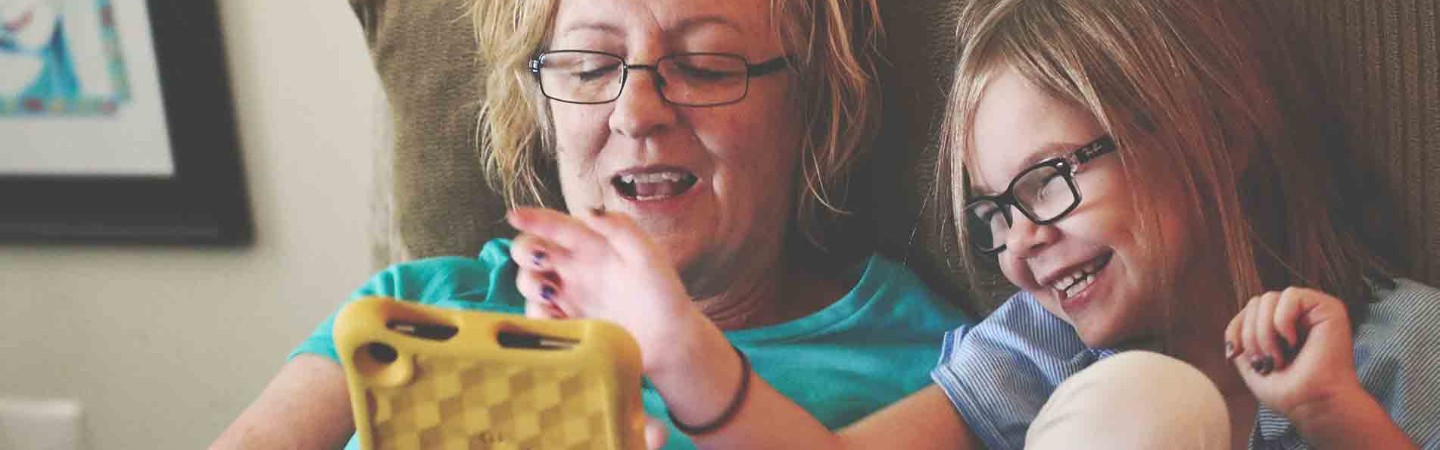 a grandmother and grandchild playing on an iPad