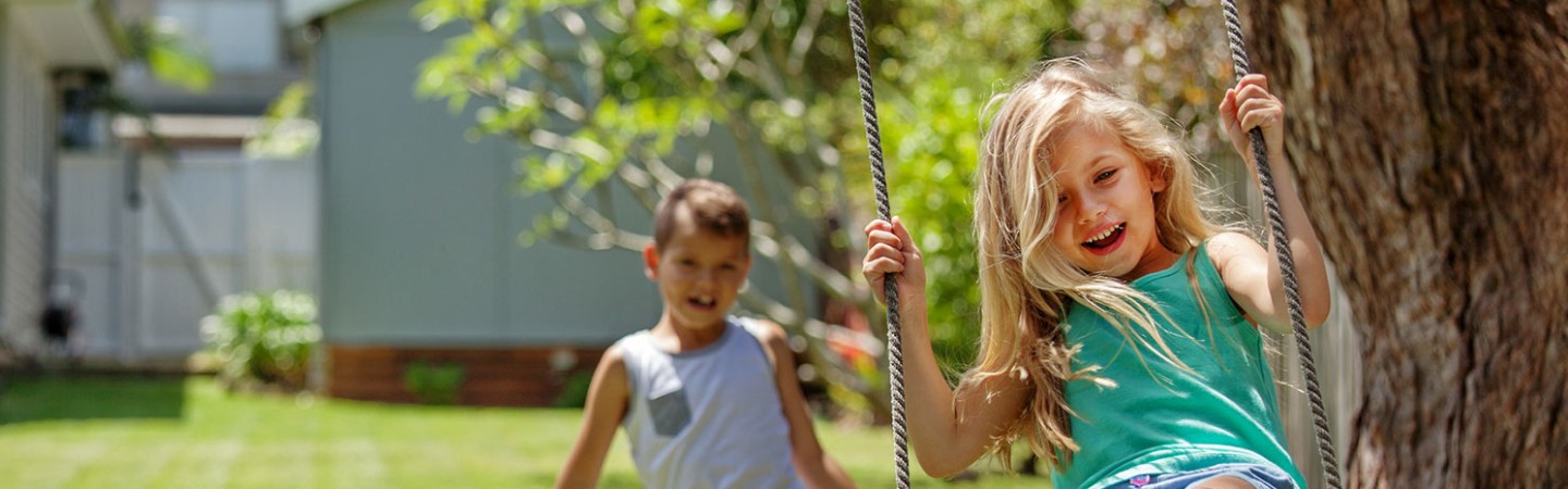 two children outside on a swing