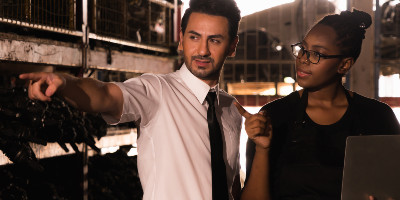 Man and women standing in manufacturing area talking and pointing