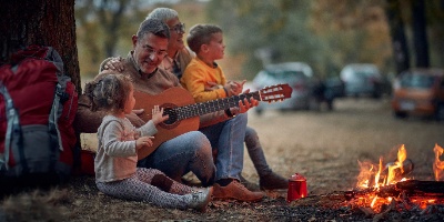 grandparents with their grandchildren sitting by a campfire