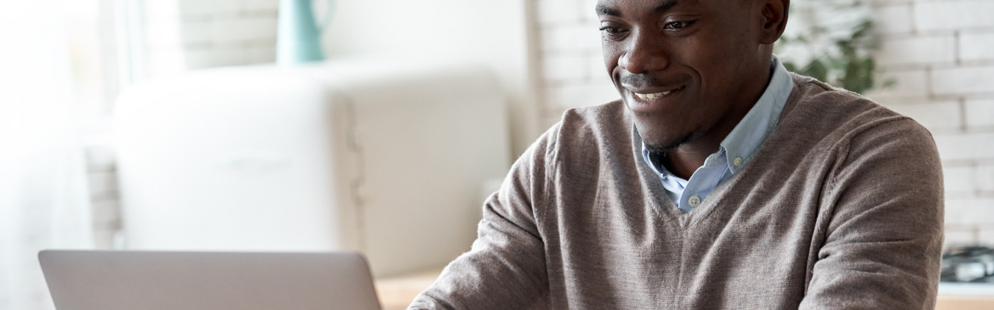 Young African American man using a laptop and smiling