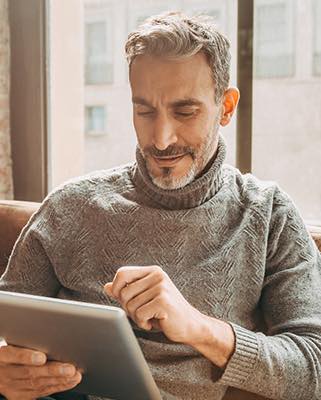 Person sitting in front of a window on a tablet.