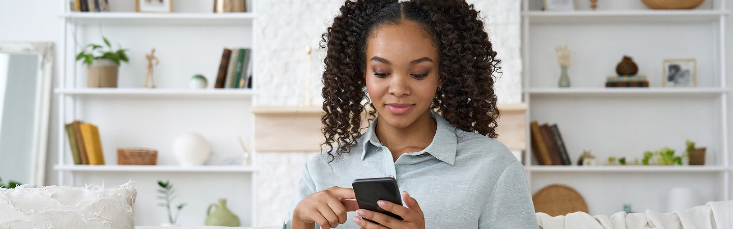 Young lady sitting on couch using her mobile phone