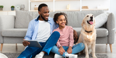 a father and his daughter sitting on the floor with their dog